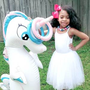 Girl in dress posing with Inflatable Unicorn Punching Bag and Ring Toss
