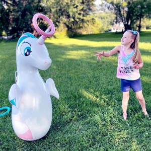 Girl throwing a ring on a Unicorn horn Inflatable Dudes® punching bag