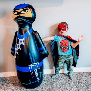 Boy in a Spiderman costume enjoying playtime with the NOBI kids punching bag.