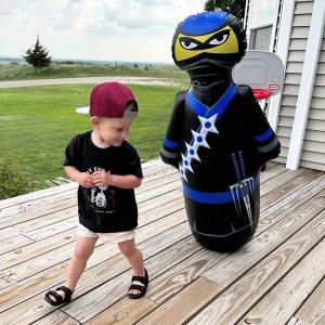 Young boy outdoors walking with the Inflatable Dudes® Ninja NOBI kids punching bag.